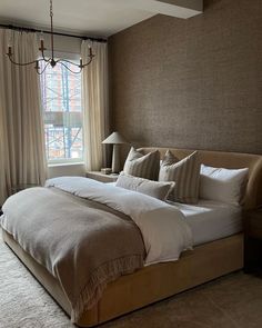 a large bed sitting in the middle of a bedroom next to a window with curtains