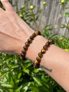 Tiger's Eye Beaded Bracelet 8mm round beads Tiger's Eye, a crystal with glowing bands of yellow golden hues that brings strength and will power! A stone of protection, Tiger's Eye is believed to be watching over its' people and 'keep an eye open' for them!  Approx. 7inches around/ The bracelets are stretchy and fits most peoples' wrists.  Also sometimes referred as Tiger's Eye, Tiger Eye, Cat's Eye. This listing for one (1) Tiger's Eye stretchy bracelet. Thank you for checking out this listing! This treasure helps support my small business and my mission to recycle and reduce waste in our city! Orders over $35 get FREE shipping! To stay updated with new items follow us on Instagram @Tumbledshop  OR Click the link below!  https://www.instagram.com/tumbledshop/ Tigers Eye Bracelet Men, Adjustable Spiritual Crystal Bracelet With Polished Beads, Brown Gemstone Beads Crystal Bracelet For Healing, Brown Crystal Bracelet With Gemstone Beads For Healing, Hypoallergenic Holistic Beaded Bracelets, Spiritual 8mm Beads Wristband For Healing, Spiritual Round Beads Hypoallergenic Bracelet, Spiritual Healing Evil Eye Bracelet With Round Beads, Spiritual Hand-strung Evil Eye Bracelet For Healing