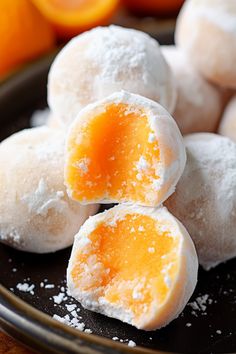 powdered sugar coated pastries on a plate with oranges in the background