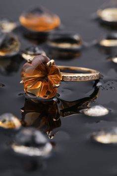 an orange ring sitting on top of a black surface with drops of water around it