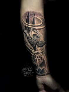 a man's arm with a tattoo on it that has an egyptian mask in the middle