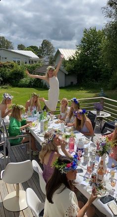 a group of women sitting around a table with flowers in their hair and plates on the table