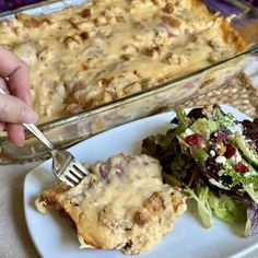 a person holding a fork near a plate with food on it and a casserole dish in the background