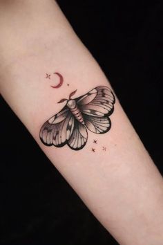 a small butterfly tattoo on the arm with stars and a crescent moon behind it's wings