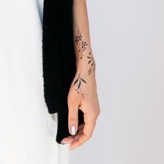 a woman's hand with a tattoo on her left arm and the other half of her wrist