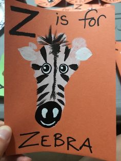 a child's hand holding up a card with an image of a zebra on it