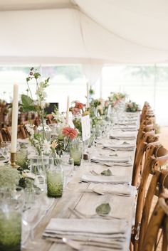 a long table is set up with place settings and flowers in vases on the tables