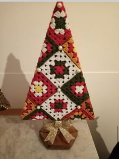 a crocheted christmas tree sitting on top of a marble table next to a wall