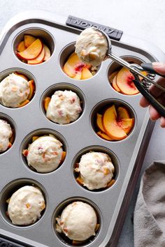 a muffin tin with peaches and ice cream in it being held by a pair of tongs