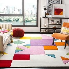 a living room with colorful rugs and modern furniture in the corner, along with large windows