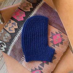 a blue knitted sweater sitting on top of a brown leather bag next to a purse