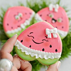 two decorated cookies in the shape of watermelon slices are being held by someone's hand