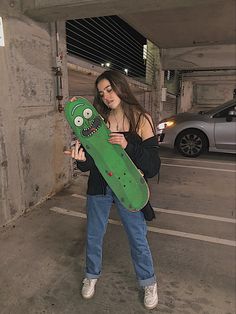 a woman holding a skateboard in an empty parking garage with her face painted on it