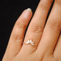 a woman's hand with a ring on it that has three small white flowers