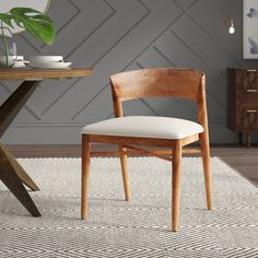 a wooden chair sitting on top of a rug next to a table with a potted plant