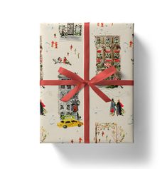 a present wrapped in wrapping paper with a red bow on it's side and decorated with christmas images