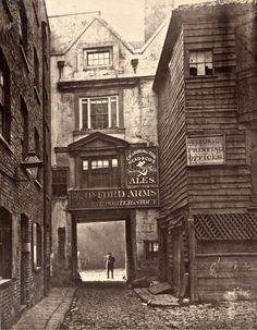 an old black and white photo of people walking down the street in front of buildings