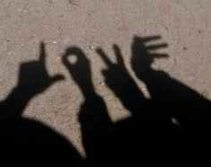 the shadow of two people holding their hands up