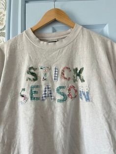 a white t - shirt with the words sick season on it hanging from a hanger