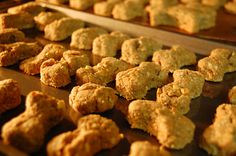 several trays of food that are on top of a wooden table and one is filled with muffins