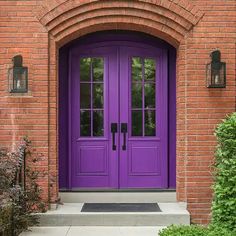 a purple front door with two sidelights on the brick wall and an arched doorway