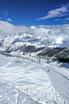 a person riding skis down a snow covered slope with mountains in the back ground