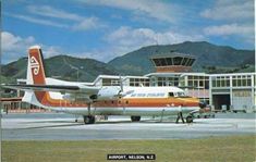 an orange and white airplane is on the tarmac at an airport with mountains in the background