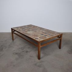 a coffee table made out of wood and stone tiles on the top, sitting in an empty room