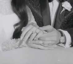 black and white photograph of a bride and groom holding each other's hands while sitting at a table