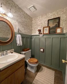 a bathroom with green walls and wood trim around the toilet, sink, and mirror