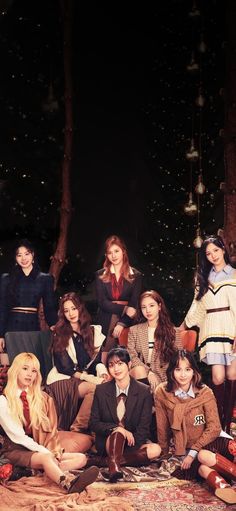 a group of young women sitting on top of a rug next to each other in front of christmas lights