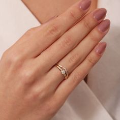 a woman's hand wearing a gold ring with two diamonds on the middle finger