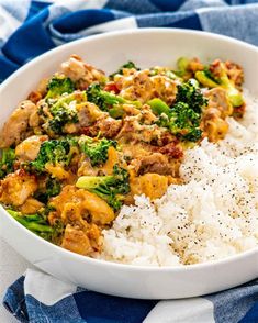 a white bowl filled with rice, broccoli and meat on top of it