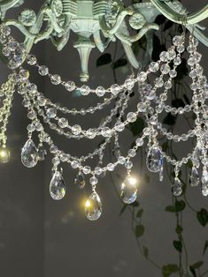 a chandelier hanging from the ceiling in a room with flowers and greenery