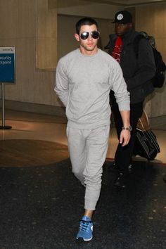 a man wearing sunglasses is walking through an airport with another man in the back ground