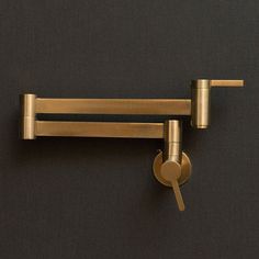 a pair of brass - plated hooks hang on a black wall