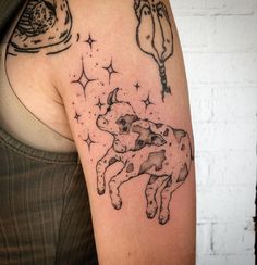 a woman with a tattoo on her arm has a cow and stars in the sky