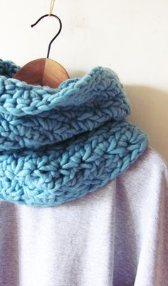 a blue knitted scarf hanging on a wooden hanger