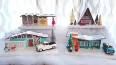 three small houses with cars and trees on top of snow covered ground next to a window