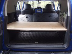 the back end of a blue van with a wooden table in it's trunk