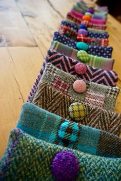 a row of multicolored knitted scarves with pom - poms