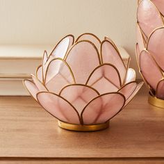 two pink and gold vases sitting on top of a wooden table next to each other