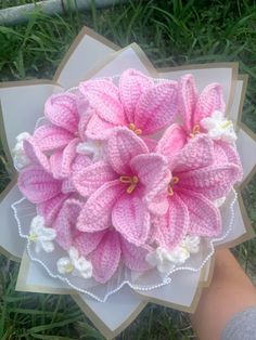 a crocheted pink flower on top of a piece of paper in the grass