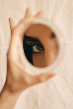 a woman's eye is seen through a magnifying glass with her hand