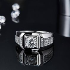 a white gold ring with diamonds on a black surface next to some other jewelry items