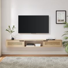 a flat screen tv mounted to the side of a wall in a living room next to a potted plant