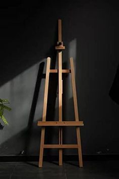 an easel leaning against a wall with a potted plant in the foreground