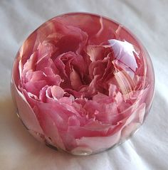 a pink flower in a glass bowl on a white tablecloth with a fork and spoon