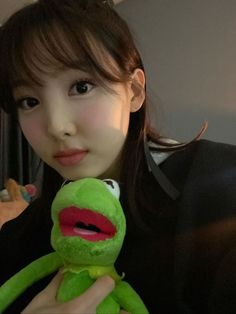 a woman holding a green stuffed animal in her hands