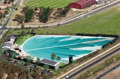 an aerial view of a large swimming pool in the middle of a city with lots of green grass